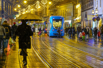 Pedestrians cross festive shopping street in before tram drives through the city © helivideo