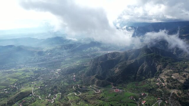 A flight and a view from the cockpit through low-hanging clouds. The fog lifts over the Aspromonte National Park in southern Italy, revealing winding mountain roads.