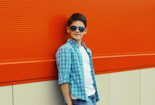 Modern teenage kid boy in casual clothes with glasses standing in the city