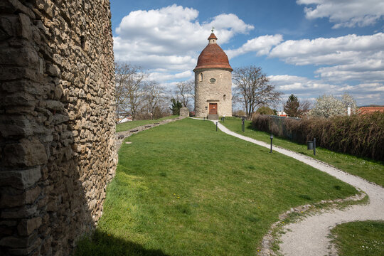 The Romanesque Rotunda of St. George in Skalica, Slovakia, with ancient stone fortification walls under a bright blue sky with clouds