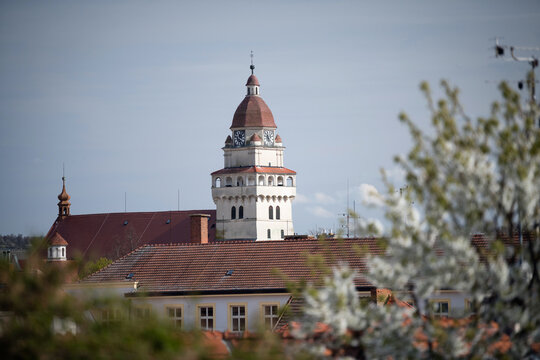 The Tower of the Parish Church of St. Michael the Archangel in Skalica, Slovakia, rising above traditional red roofs and blooming spring trees