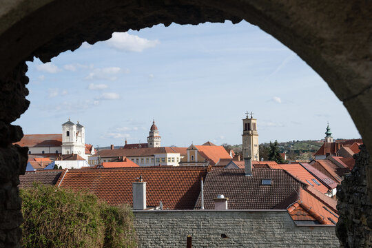 Scenic view of Skalica town skyline with historic church towers and red roofs framed by an ancient stone archway, Slovakia