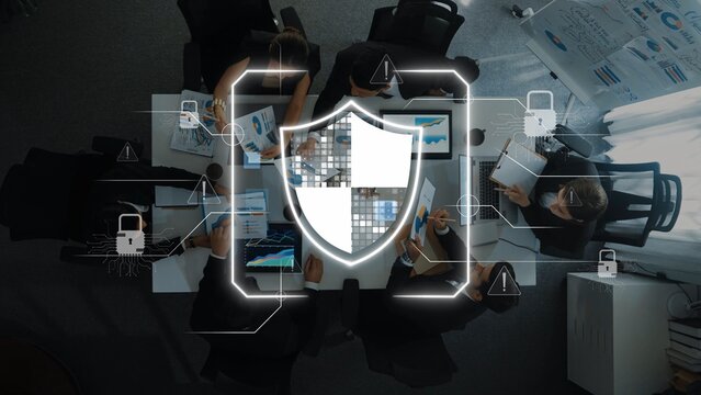 A team of professionals engages in a strategic meeting on cybersecurity, using digital devices surrounded by data visuals, emphasizing protection and teamwork. Raster