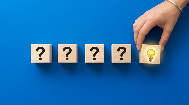 Hand placing a wooden block with a glowing lightbulb among question mark blocks on a blue background, symbolizing idea and solution.
