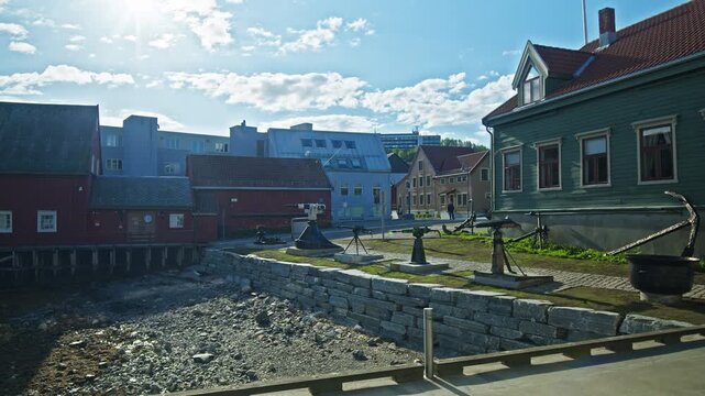 A shoreline walkway near The Polar Museum leads past colourful buildings. Red structures appear further along the harbor.