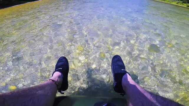 POV F&uuml;&szlig;e h&auml;ngen aus Schlauchboot w&auml;hrend schneller Rafting Fahrt auf der Isar, sommerliches Abenteuer mit Badeschuhen in Full HD