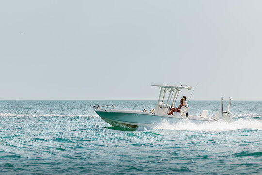 Saltwater fishing boat on a sunny summer day. Couple on recreational powerboat cruising the blue water of the Gulf of America, Florida.