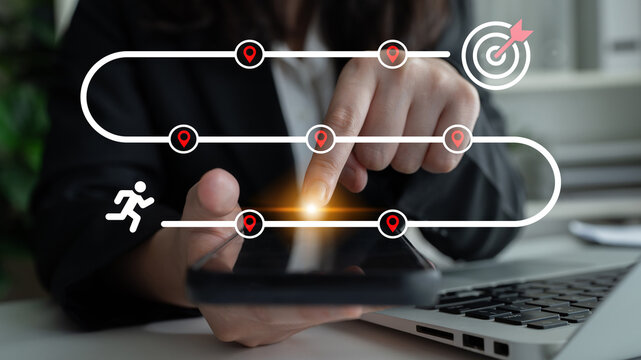 A business professional uses a smartphone to define a journey toward success, emphasizing targets and achievements in a modern office space. Ideal for themes of motivation and planning. Ledger