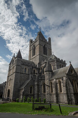 Fototapeta premium Christ Church Cathedral in Dublin with its Gothic architecture, arched windows, and central tower, set against a partly cloudy sky with a grassy area
