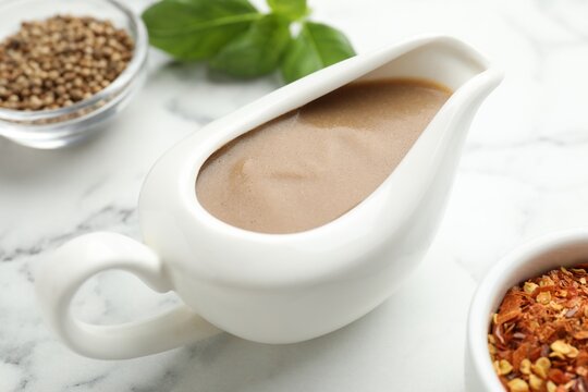 Turkey gravy in sauce boat on white marble table, closeup