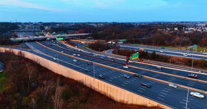 Cars riding fast by the multi-lane motorways. Several trestles are over the highways in the backdrop.