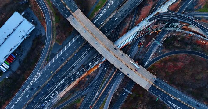 Busy interchange with lively traffic. Drone footage rising over the motorways in the intersection.