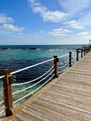 Fototapeta premium Wooden pier with rope railings leading to the turquoise Mediterranean Sea in Cyprus