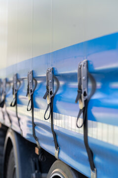Close-up of blue truck trailer curtain with tension straps and buckles, logistics and cargo transportation concept