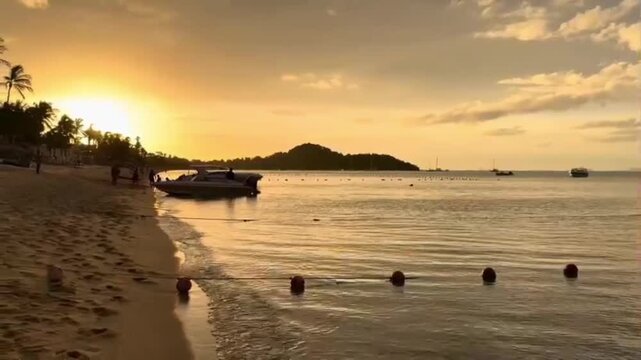 Cinematic 1080p Koh Samui sunset; slow pan from ocean yachts to golden sun and palm trees. Tourists disembarking from boat on shore. Authentic tropical travel for luxury brand marketing.