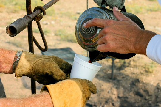 Pouring Coffee from Metal Pot into Cup Over Outdoor Campfire