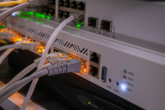 Close-up of network equipment with ethernet cables connected to router and switch. Data center hardware, IT infrastructure and communication technology concept.