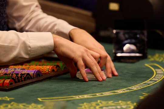 Casino dealer shuffling cards at blackjack table with poker chips