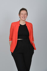 Fototapeta premium Selbstbewusste Geschäftsfrau im roten Blazer vor neutralem Hintergrund, modernes Business-Porträt mit Ausstrahlung und Copyspace