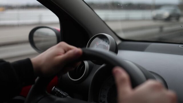 Close up of driver hands on steering wheel with road moving ahead through windshield dynamic motion travel and transportation concept everyday driving experience