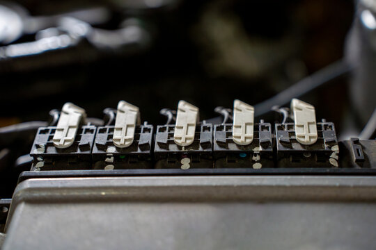 Close view of an automotive electronic control unit with wiring harness and connectors installed in a car engine compartment during service inspection.