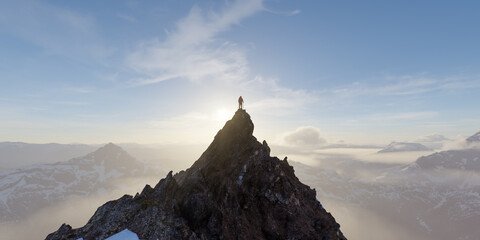 Climber on Mountain Summit at Sunrise Standing on Rocky Peak Over Misty Alpine Landscape © edb3_16