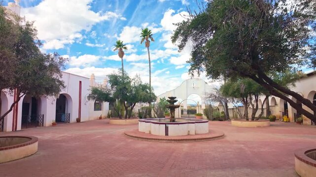 Decorative fountain stands in front of Mission San Xavier del Bac with Spanish Catholic architecture under bright sunlight in Tucson Arizona