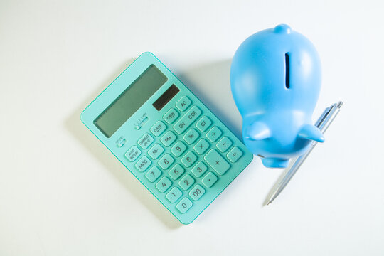 Blue piggy bank with calculator and pen on a white background.