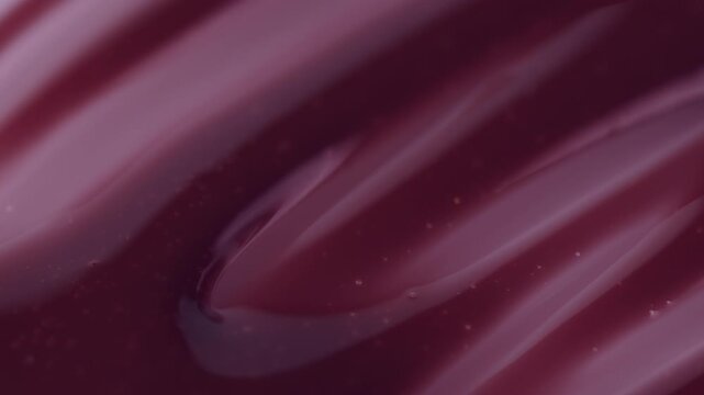 Macro shot of glossy purple cosmetic lipstick texture applicator