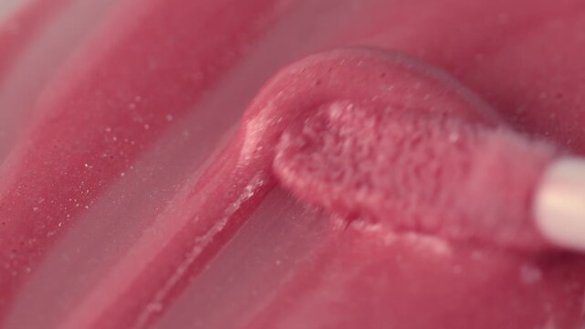Macro shot of glossy pink cosmetic lipstick texture applicator