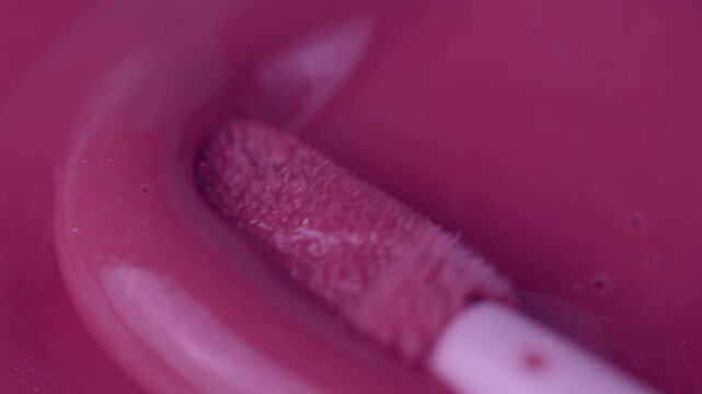 Macro shot of glossy pink cosmetic lipstick texture applicator
