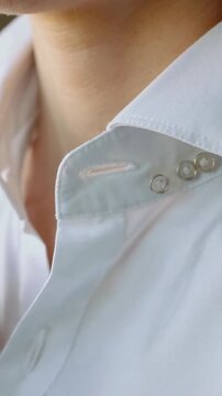 Vertical video: Preparing, manicured hand lifting white shirt collar at home showing red stitch