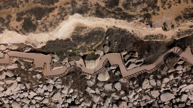 Breathtaking aerial drone footage of the Rock Trail in Aktau, Mangystau. A wooden promenade elegantly built over coastal rocks and cliffs of the Caspian Sea. Bright sunny summer day