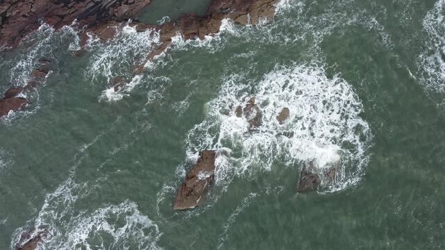 arbroath city and cliffs east coast of scotland dramatic epic rugged scenery backwards moving drone shot red sandstone cliffs stormy sea waves over rocks