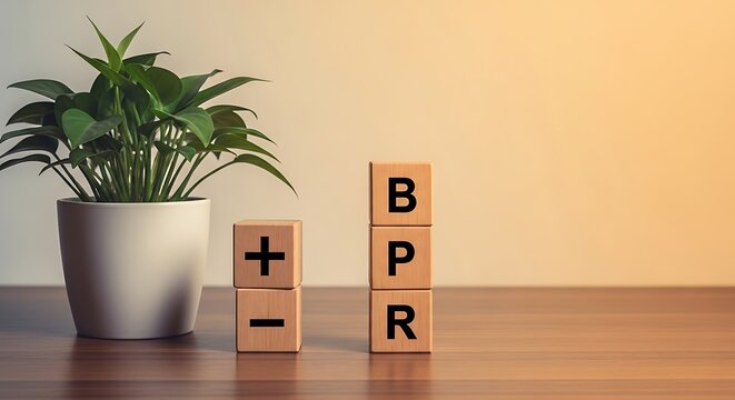 Wooden blocks spelling bpr next to a plus and minus sign on a desk with a plant
