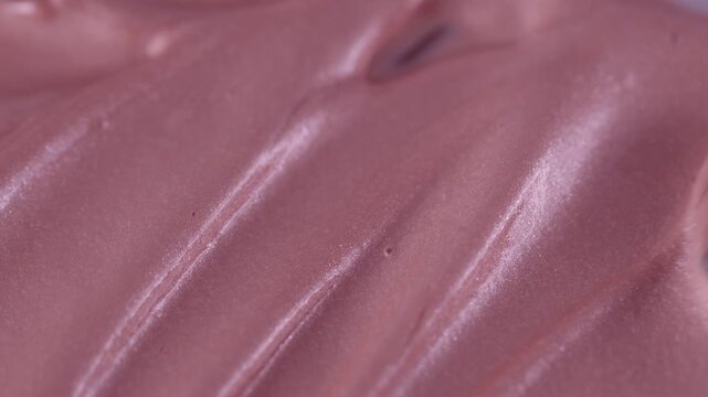 Macro shot of glossy pink cosmetic lipstick texture applicator