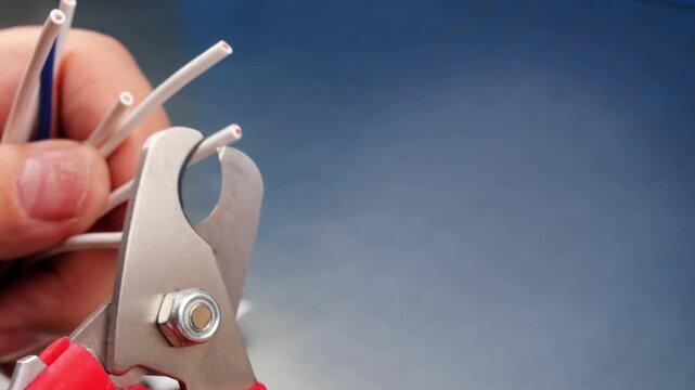 Cutting copper electrical wires with wire cutters. 