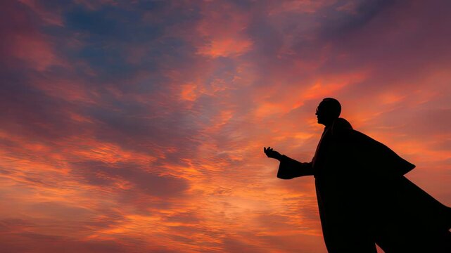 Silhouette of a Figure with Outstretched Arms Against a Vibrant Sunset Sky with Shades of Orange, Pink, and Purple Clouds