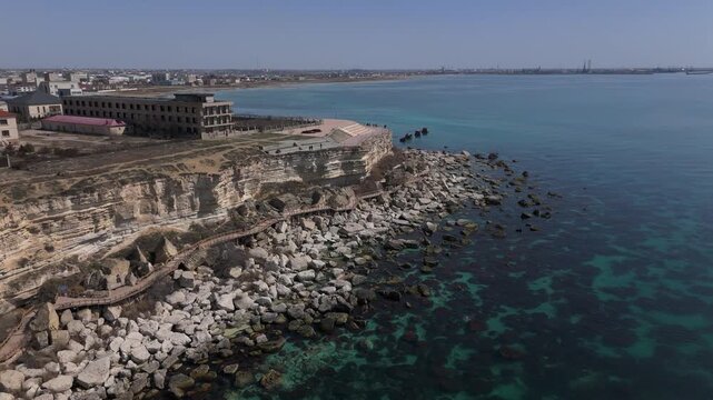 Aerial View of Scenic Rocky Cape in Aktau City on Caspian Sea Coast, Kazakhstan. Modern Buildings on the Edge of High Cliffs with Wooden Pedestrian Promenade
