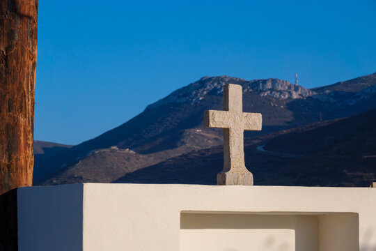 Stone cross on white building with mountain backdrop, Amorgos, Greece