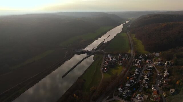 Wasserkraftwerk Kelheim Luftaufnahme. Aerial footage of Kelheim lock and Wasserkraftwerk Kelheim on Main-Donau-Kanal. Golden hour autumn light over river, canal infrastructure. Schleuse Kelheim