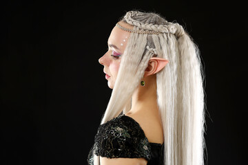 Obraz premium Beautiful girl dressed as elf on black background