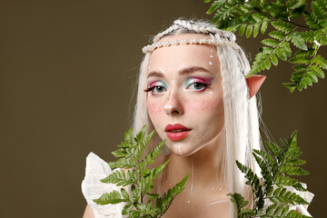Obraz premium Beautiful elf girl with floral decor on dark olive background, space for text