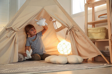 Little girl playing with toys in wigwam at home © New Africa