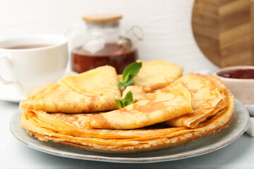 Tasty crepes with mint leaves and jam served on white table, closeup © New Africa