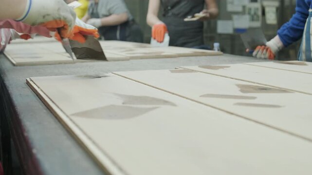Detailed shot of lumber boards stacked together with a shallow depth of field and a blurred carpenter working in the background
