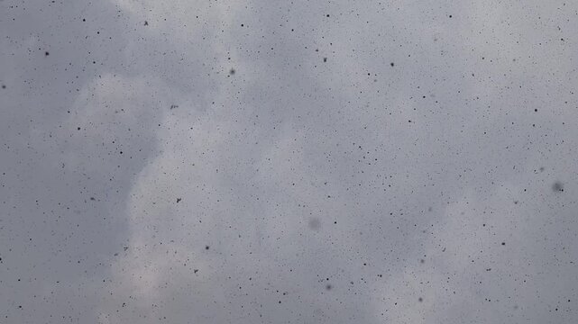 Volcanic ash and cinders raining down from a cloudy sky during an eruption, creating a surreal and apocalyptic atmosphere of environmental fallout and pollution