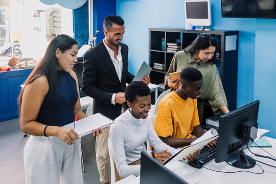Diverse group of young university students and hispanic teacher using computer in an Academic Environment. Multicultural latin people in technology class in classroom in Latin America