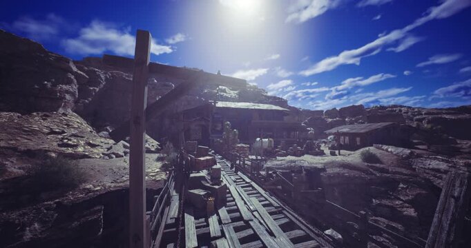 Rustic wooden tracks lead through an abandoned mining town, where remnants of carts are scattered. Sunlight brightens the rocky landscape against a clear blue sky, hinting at a storied past.