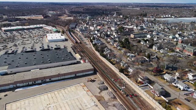 Aerial view of a MBTA Commuter Rail train amidst a landscape with buildings and bare trees, Braintree, Massachusetts, United States.